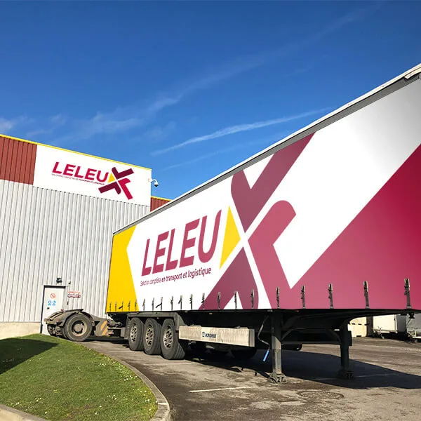 Semi-remorque aux couleurs de Leleu Transports et Logistique devant un entrepôt